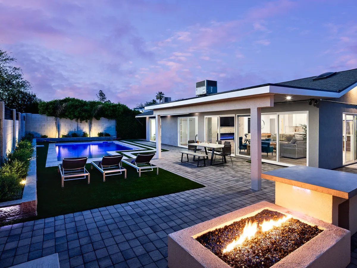 The hero image showcases a modern Scottsdale home with a sparkling swimming pool, inviting outdoor seating area, a glowing fire pit, and stylish house exterior. The scene is set at sunset, highlighting warm desert skies and a cozy, social atmosphere perfect for entertaining or relaxing with friends and family.