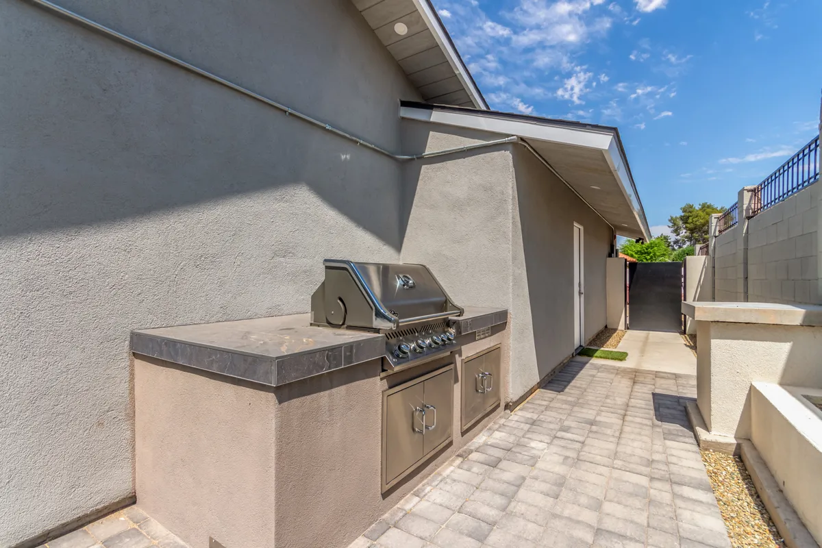 A dedicated grilling area with a sleek barbeque setup and a paved pathway, surrounded by privacy walls. This spot is designed for outdoor cooking and entertaining, making it perfect for sunset barbecues and casual get-togethers.