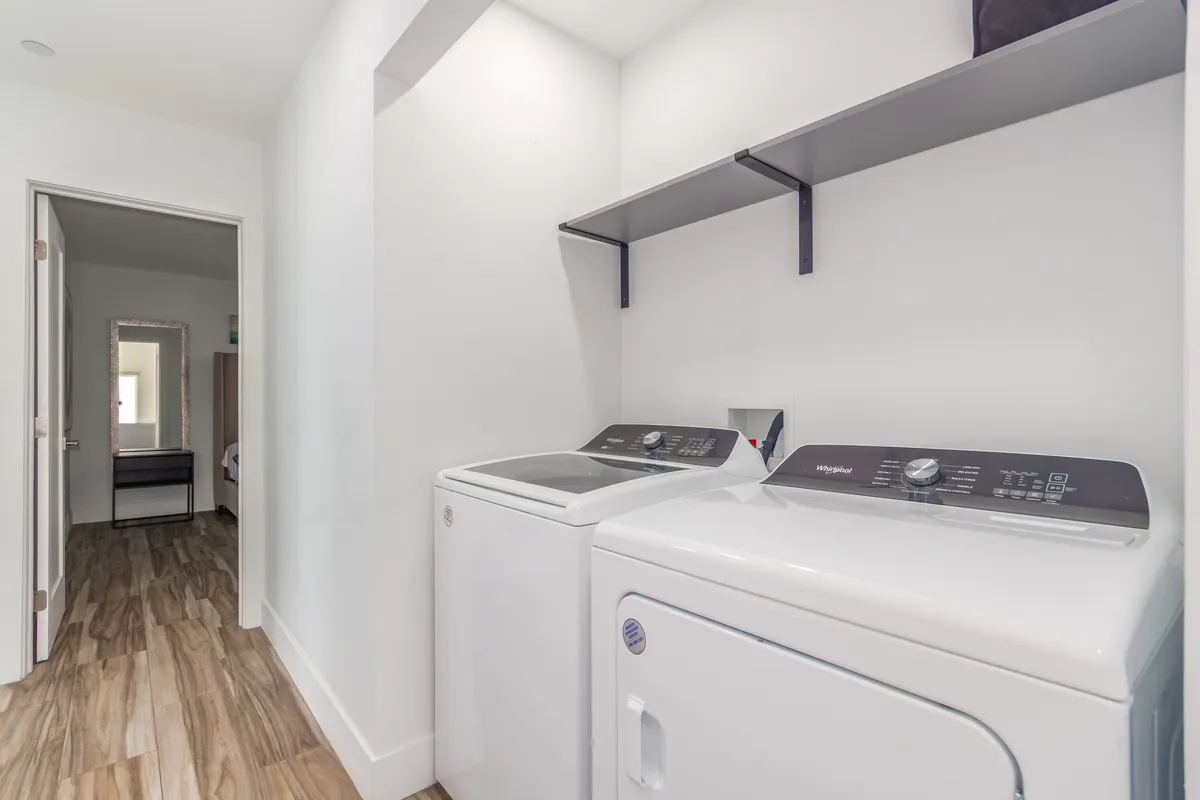 A practical laundry area featuring a washing machine, dryer, and shelving for supplies. The space is well-organized and designed for easy use, contributing to the overall sense of comfort and convenience.