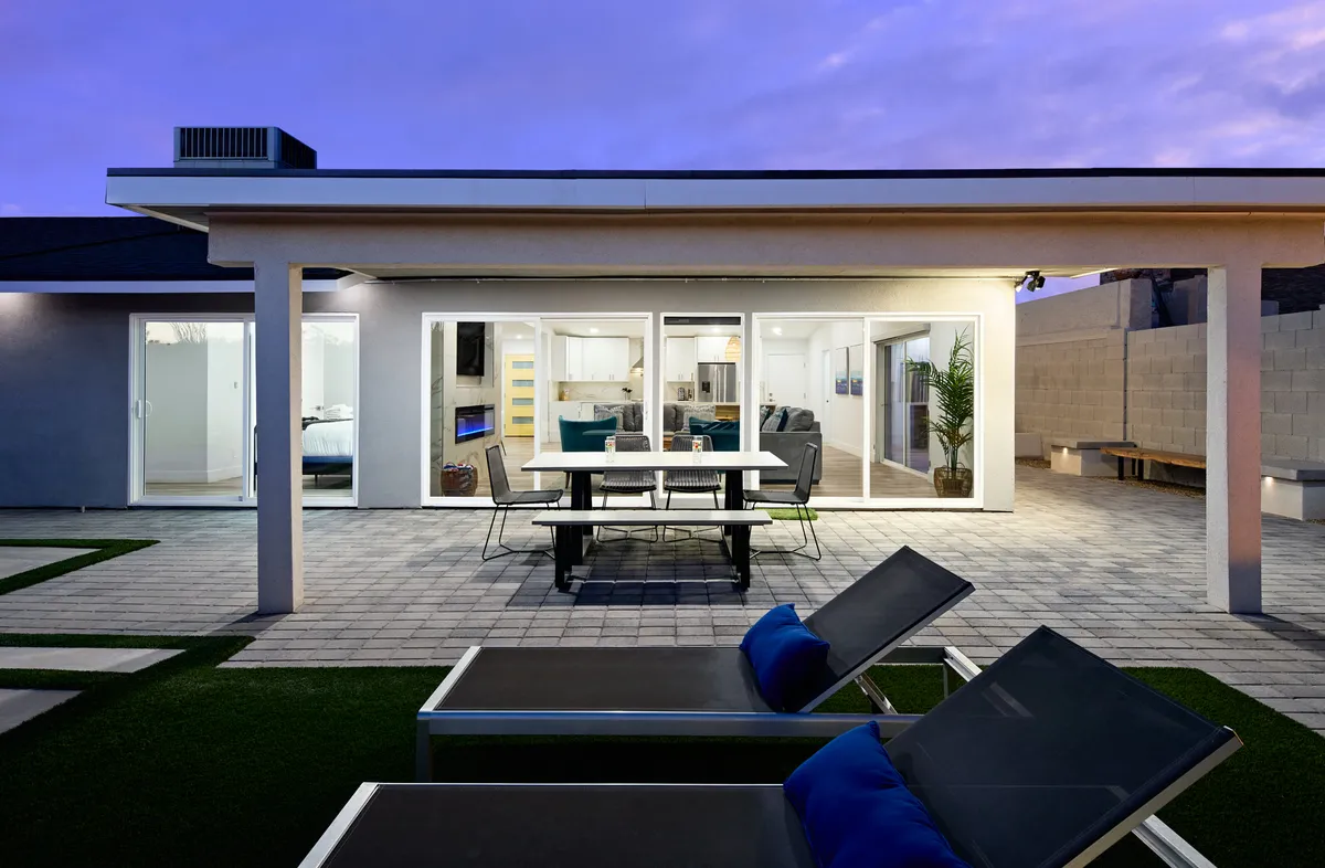 A stylish patio with modern outdoor furniture and a large dining table set against expansive sliding glass doors. The area is ideal for al fresco dining, lounging, and soaking up the Scottsdale sun, with views that hint at the adjacent pool area.